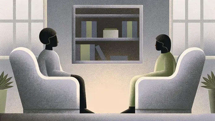 Deux personnes face à face dans des fauteuils devant une bibliothèque - séance de coaching psycho-spirituel pour briser les schémas répétitifs